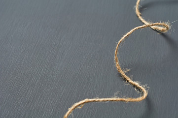 Old curly brown rope lies on dark concrete desk in workshop. Space for text