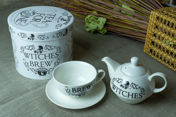 Witch tea party, white teapot and cup on gray linen  tablecloth