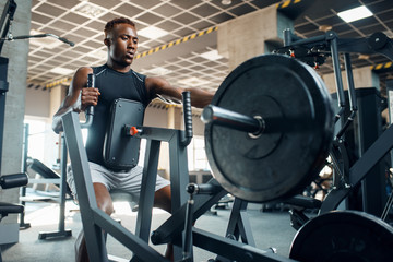 Muscular sportsman at exercise machine in gym