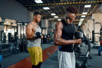 Fototapeta na wymiar Two athletes doing exercise with dumbbell in gym