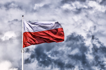 National flag of Poland waving on a dark cloudy sky background (HDR effect)