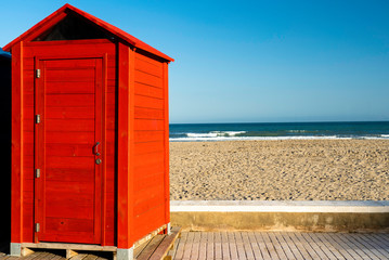 red beach hut cabin with see and beach on the background