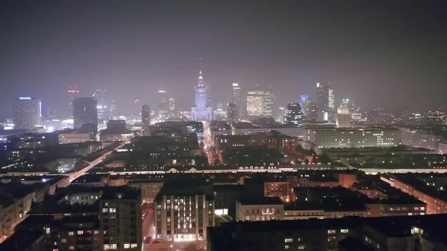 Aerial view of a cityscape on a foggy night in the center of Warsaw-Poland. Drone flies over the nightly architecture of downtown Warsaw.