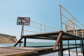 entrance of a pier located on the coast of a beach with a sign that says: entry is prohibited