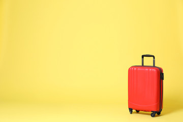 Stylish red suitcase on yellow background. Space for text