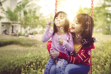 Mother holding her daughter happily while swinging