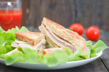 close up of club sandwiches on plate on wooden table. Salami, lettuce and cheese club sandwich on toasted bread.