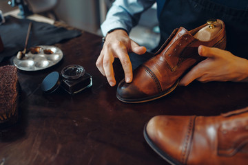 Shoemaker applies shoe polish, footwear repair