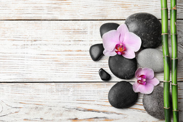 Stones, bamboo, orchid flowers and space for text on white wooden background, flat lay. Zen lifestyle
