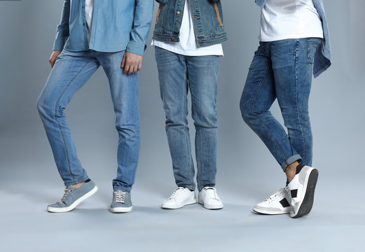 Group of young men in stylish jeans on grey background, closeup