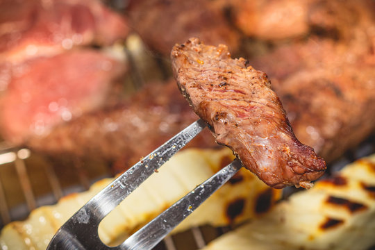 Churrasco brasileiro. Carne de churrasco sendo segurada com um grande garfo. Comida brasileira, cozinha brasileira, Brasil.