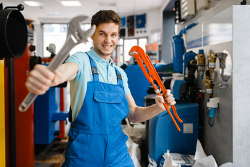 Fototapeta premium Plumber shows pipe wrenches in plumbering store