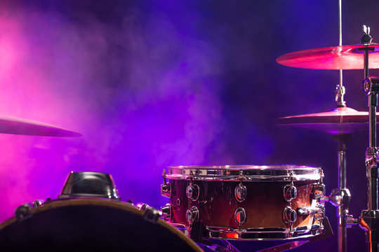 Drums and drum set. Beautiful blue and red background, with rays of light. Beautiful special effects of smoke and lighting. Musical instrument. Close-up photo.