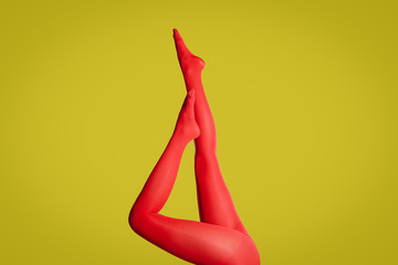 Woman wearing red tights on yellow background, closeup of legs
