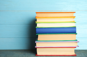 Stack of colorful books on light blue wooden table