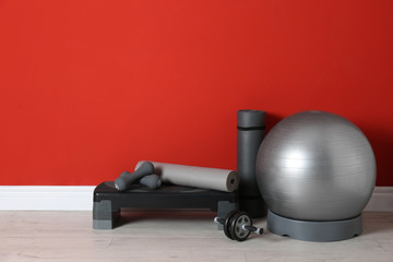 Different sports equipment near red wall in gym. Space for text