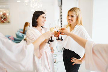 Group of girlfriends clink glasses in beauty salon