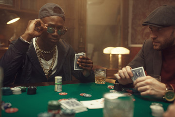 Two poker players with cards in casino