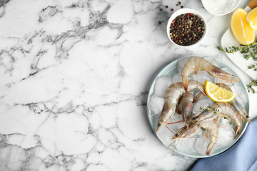 Flat lay composition with raw shrimps on marble table. Space for text