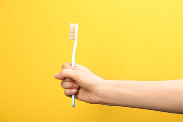 Woman holding toothbrush with natural bristles on yellow background, closeup