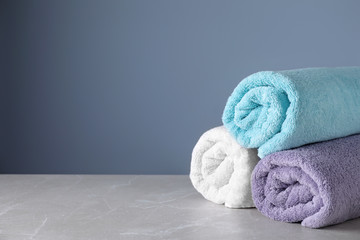 Fresh rolled bath towels on grey table. Space for text