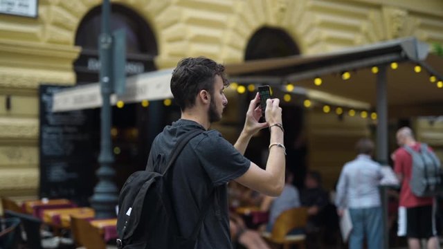 Male tourist rises phone to take pictures of Budapest with blurred background