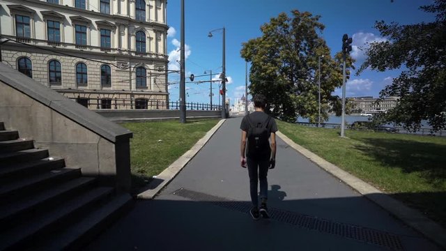 Lone man walking through tunnel to reveal Budapest on sunny day