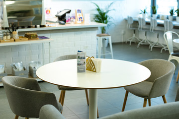 White round table with leaflet and paper napkins surrounded by armchairs