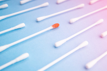 Blood on the hygiene cotton stick. Skincare mockup for design. Menstruation. Stack of disposable cotton stick on a blue background. Cosmetology concept. Bloody wound. Injury.