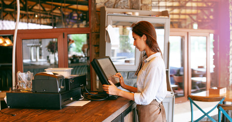 Close-up view of waitress registrated orders to the payment terminal. Young and beautiful waitress stand near sale terminal and check the order. - 311235326