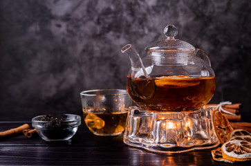 glass teapot of black tea with lemon on dark background