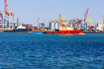 tugboat in the port of Odessa on the black sea against the background of an industrial terminal. Merchant ships on loading