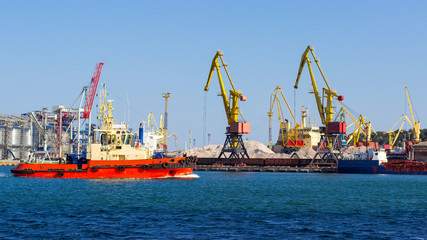 Naklejka premium tugboat in the port of Odessa on the black sea against the background of an industrial terminal. Merchant ships on loading