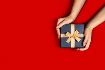 Gift box with surprise in a female hands on red background. Flat lay, top view, place for text.