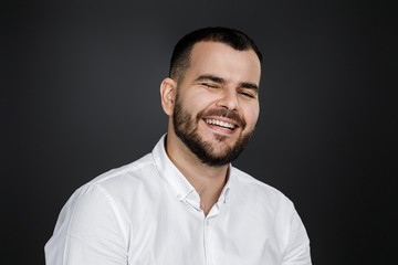 Fototapeta premium Close-up portrait of happy handsome bearded man laughing on black background