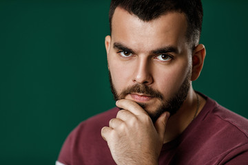 bearded man thinking about something on green background.