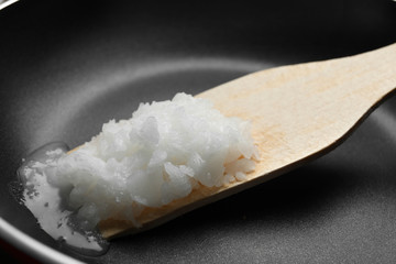 Frying pan with coconut oil and wooden spatula, closeup. Healthy cooking