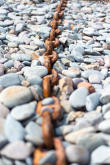 Rusty chain on pebble beach