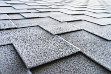 Close up view on asphalt roofing shingles covered with frost.