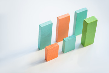 Two parallel rows of blue, orange and green flat wooden bricks making up charts