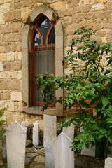 Fototapeta na wymiar Mosque window with gravestones and pokeweed bush in hillside village of Yesilyurt Malatya Turkey