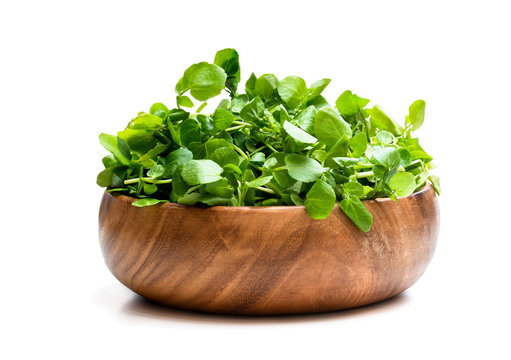 Watercress in wooden bowl isolated on white