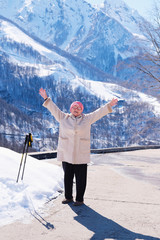 Portrait of a happy elderly woman in nature. Cute old woman smiles and does Nordic walking in the spring on a Sunny day. The way of life of the elderly the concept of retirement.