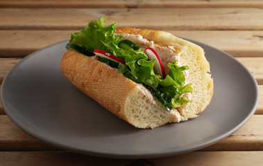 Sandwich with fresh vegetables on a ceramic gray plate. Wooden brown background. Vegetarian sandwich. Close-up.
