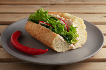 Sandwich with fresh vegetables on a ceramic gray plate. Wooden brown background. Vegetarian sandwich. Close-up.