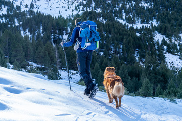 Excursionist man with his dog in a winter day with snow.