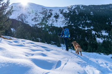 Excursionist man with his dog in a winter day with snow.
