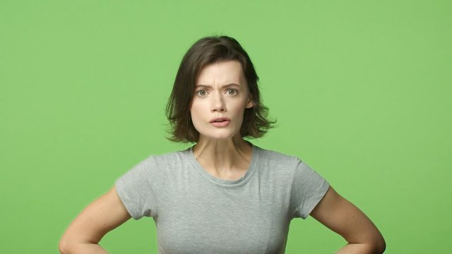Slow-motion woman hear nonsense, got surprised and shocked, looking concerned and displeased, hold hands on waist in disappointed, frustrated pose, standing green background distressed