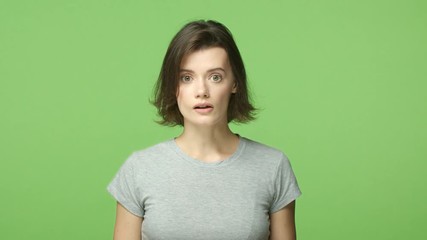 Slow-mo shocked woman in awe, open mouth astounded and wondered, gasping, holding breath startled, popping eyes camera, shopping see mush-have product, smiling in approval, green background