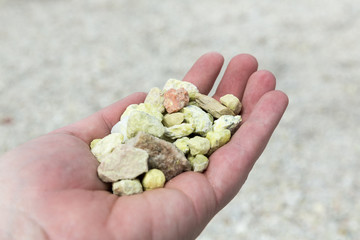 Hand holding green yellow suphur rocks from a ghost town